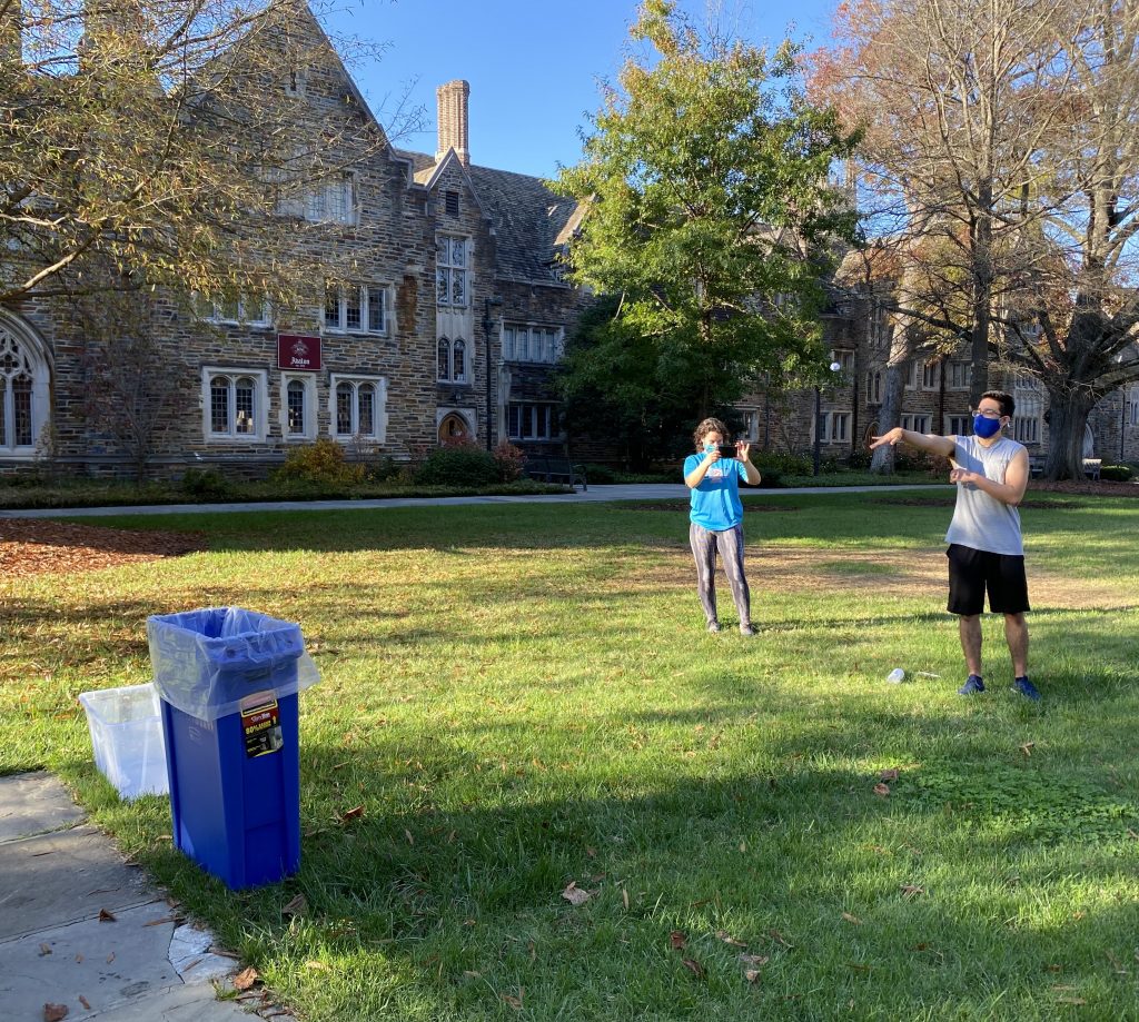 Students shooting a balled up paper with Fall 2020's trash on it at a trash can